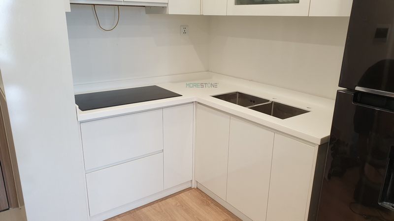 Tủ bếp có màu trắng và thiết kế dạng chữ L giúp cung cấp sự tiện dụng và tạo ấn tượng cho không gian sống của mỗi gia đình.